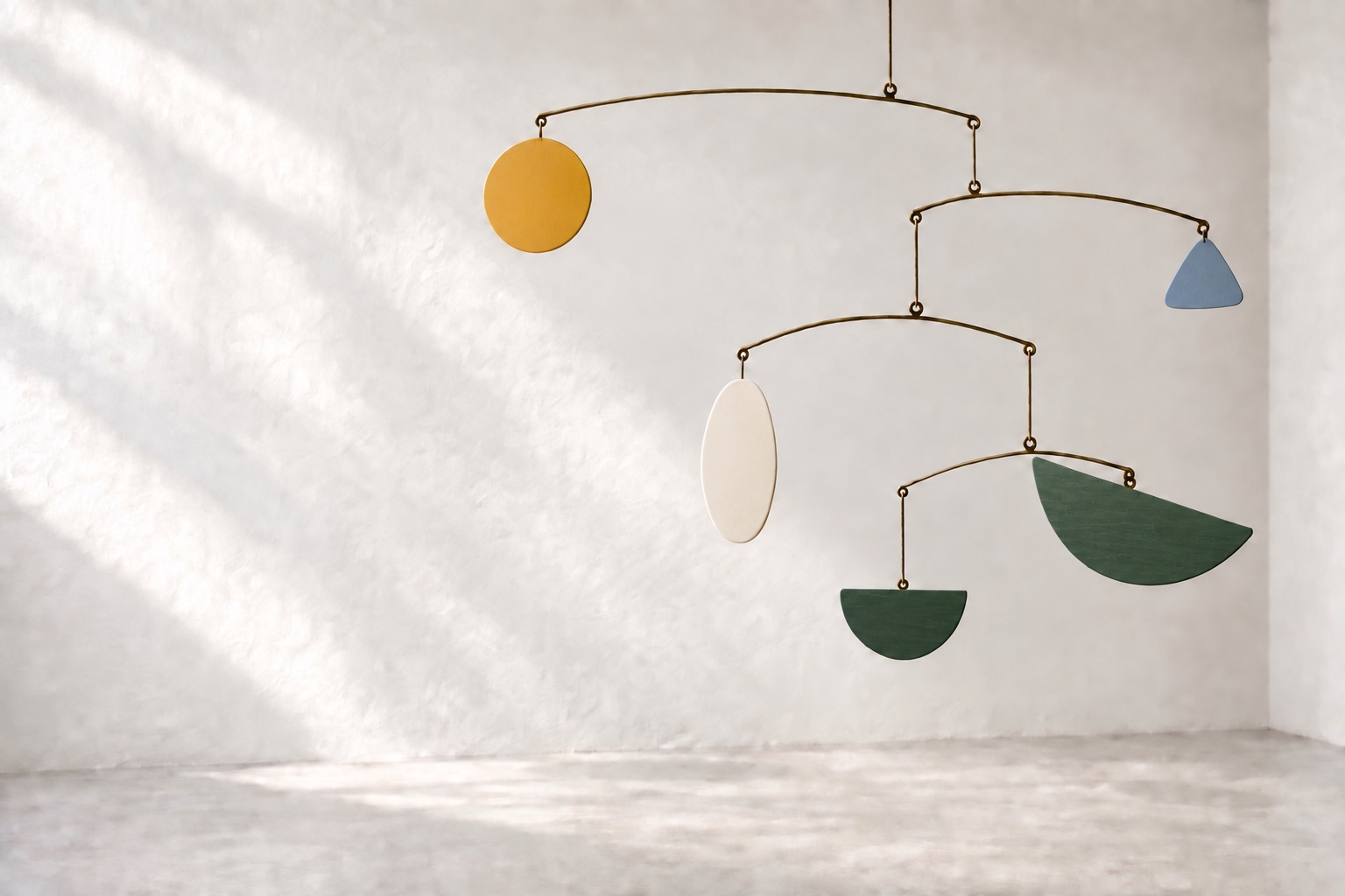 A mobile of yellow, blue, ivory, and green shapes suspended in a softly sunlit room.